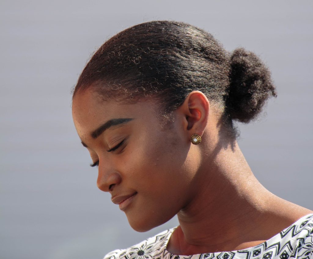 Profile of woman with black hair in a bun, looking down with a slight smile